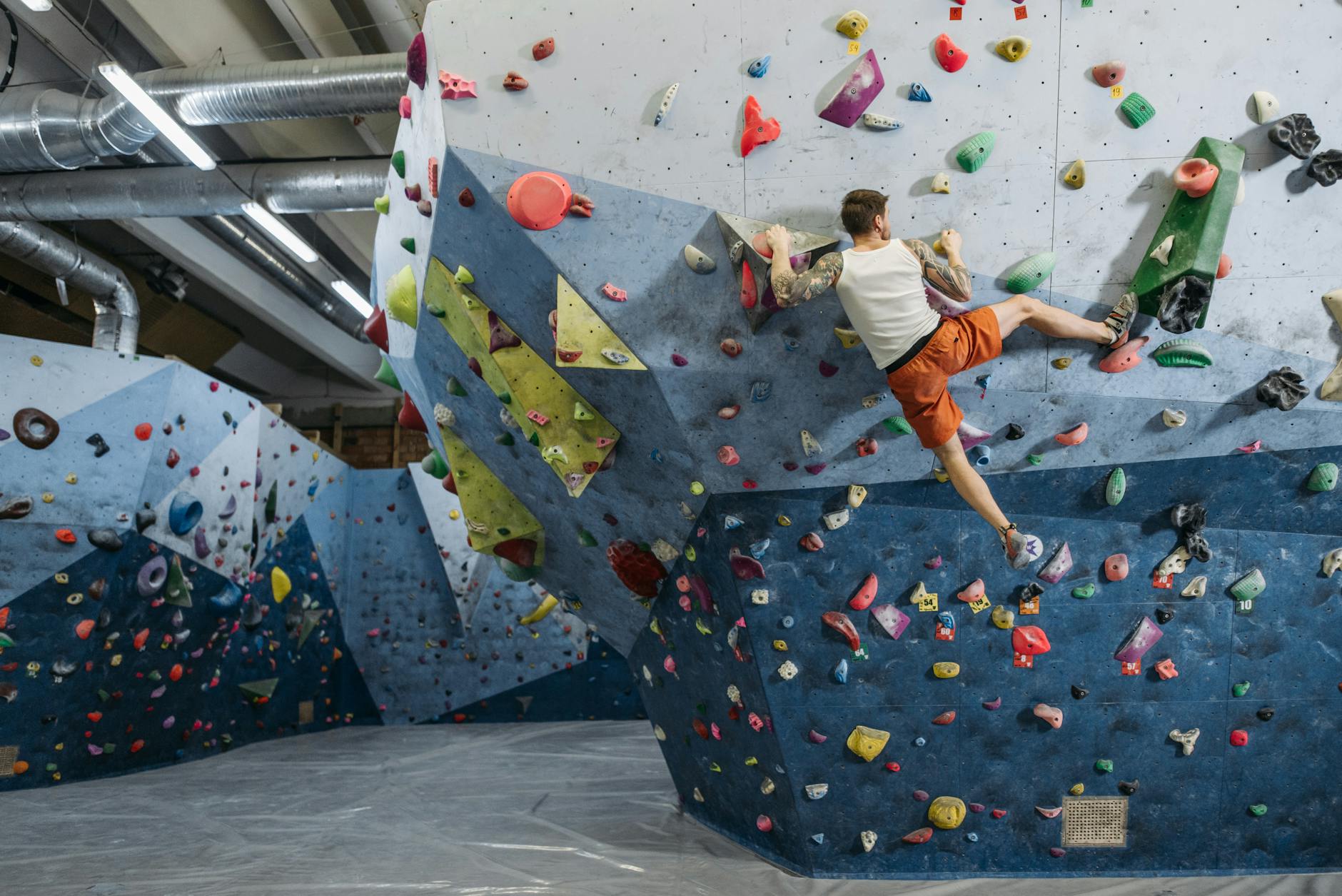 Climber bouldering on a colourful indoor climbing wall with varied holds and routes
