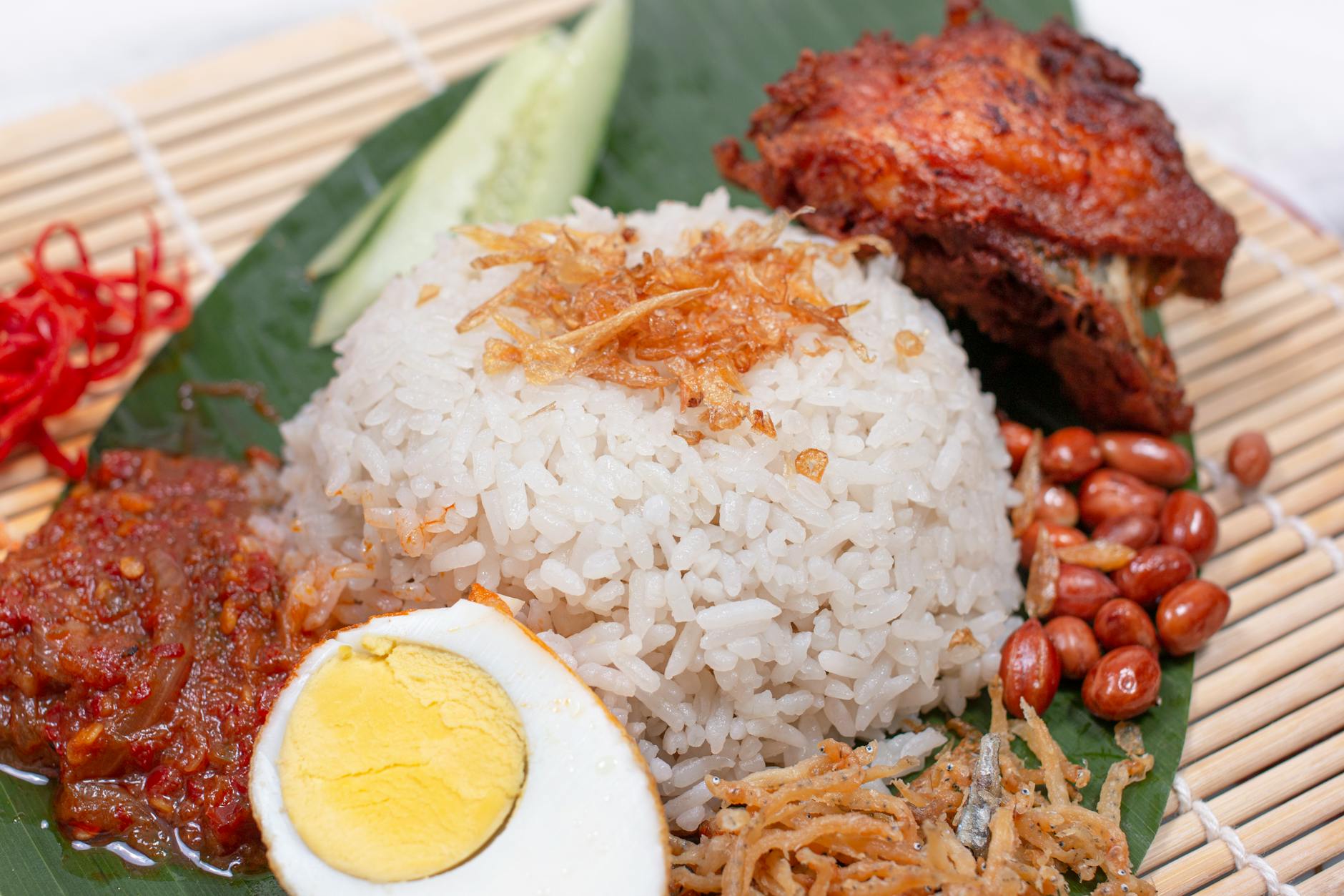 Closeup of nasi lemak showing coconut rice with sambal and traditional accompaniments