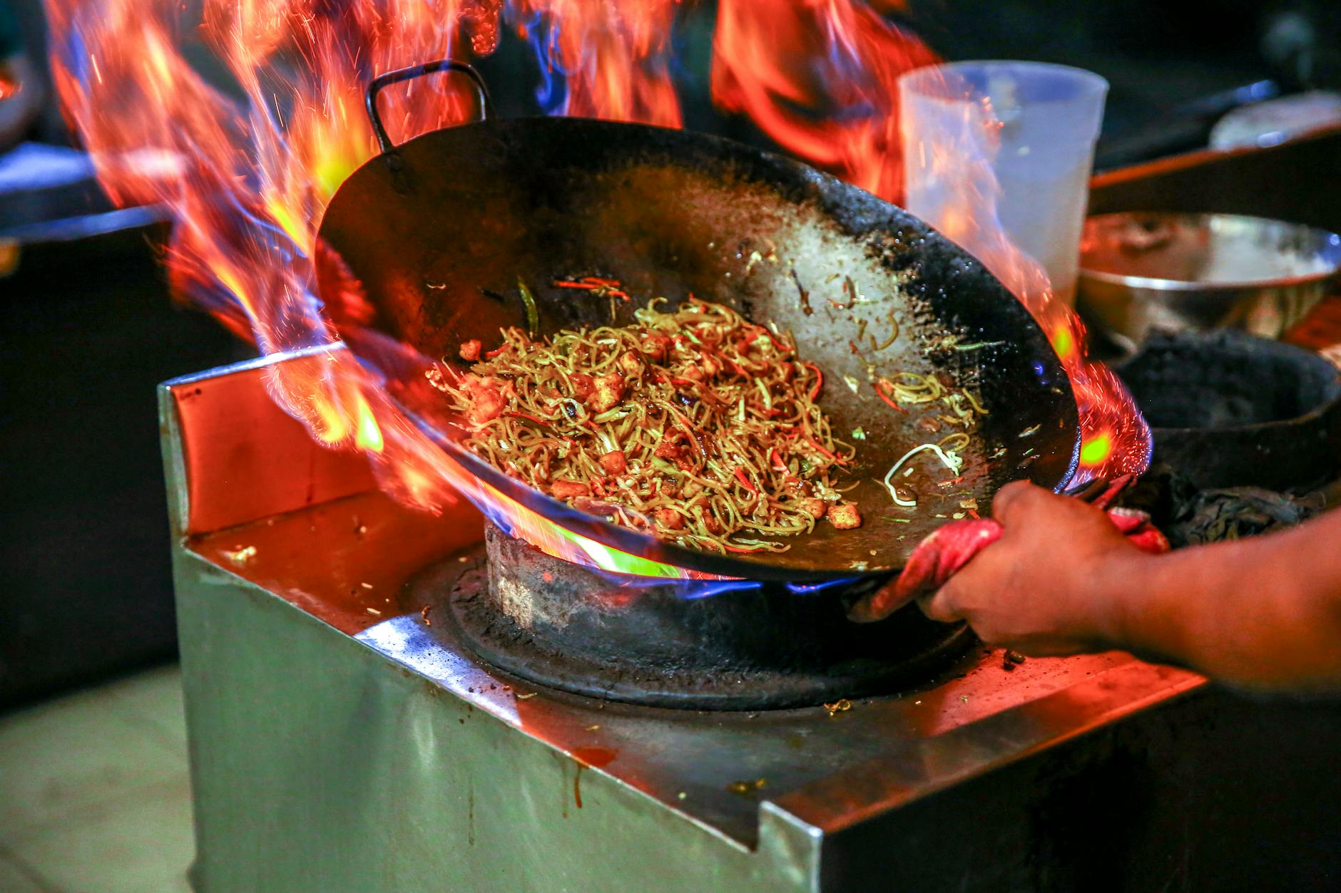 Stir-fried noodles cooking in a wok at a Penang hawker stall with smoky wok hei