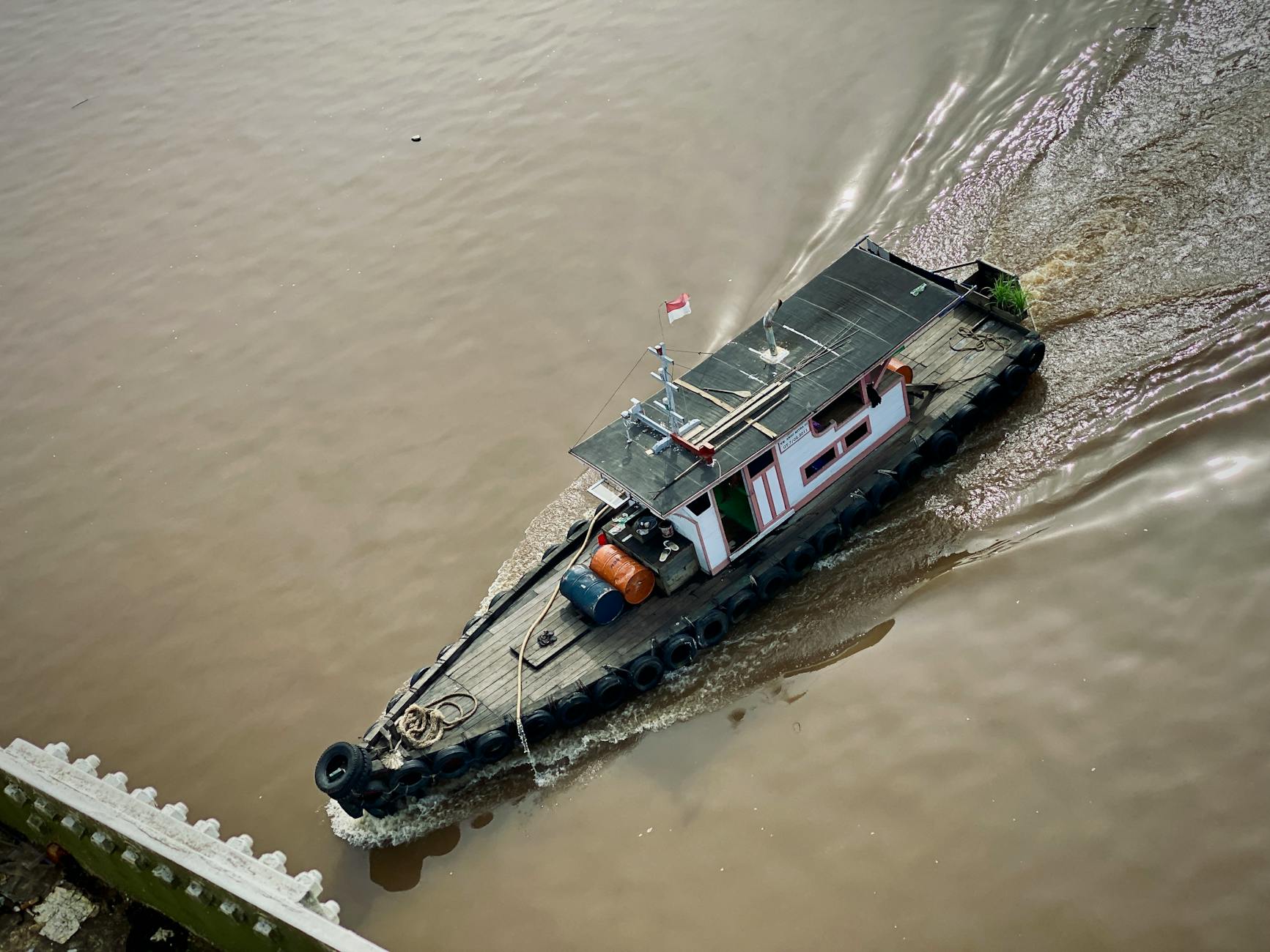 Small boat navigating a river through dense Borneo rainforest for wildlife watching