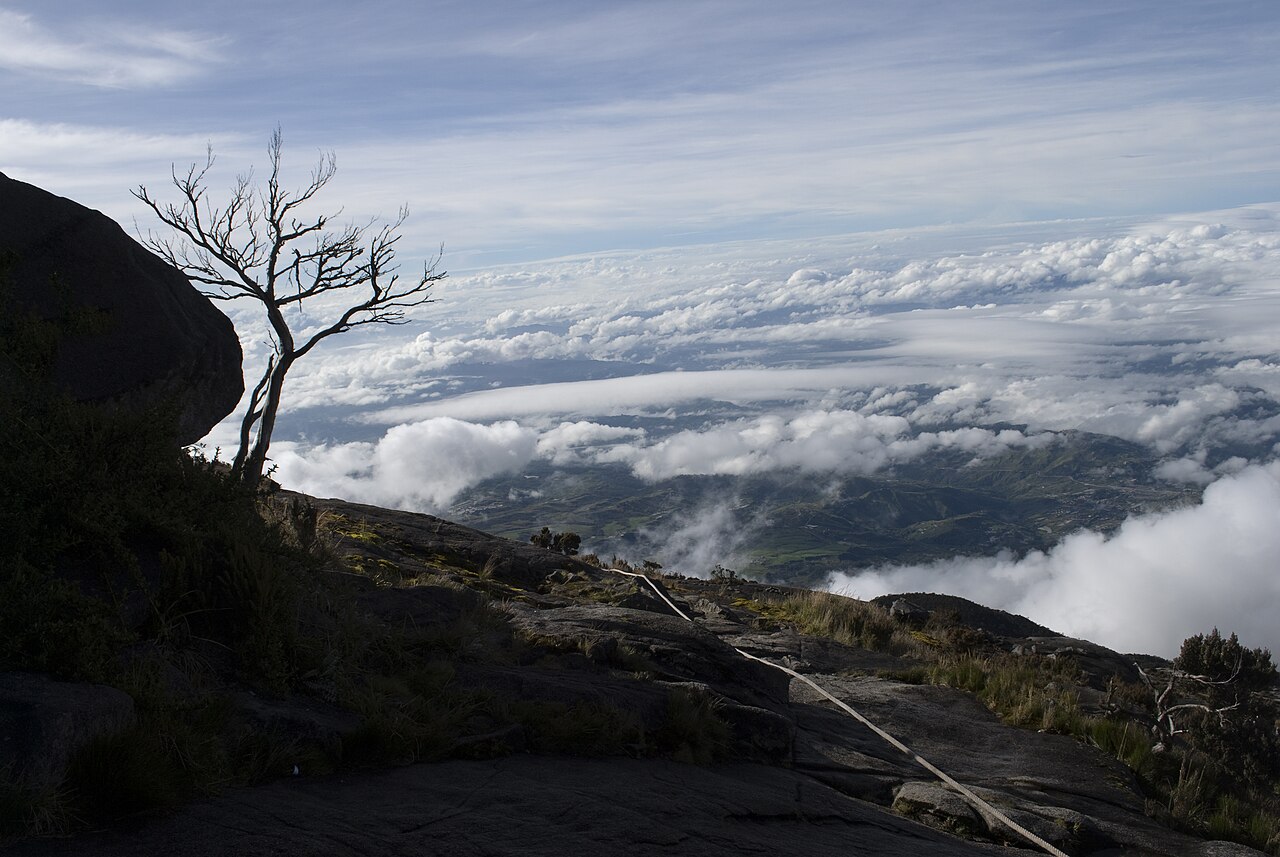 Climber on via ferrata steel cable route on Mount Kinabalu granite rock face at high altitude