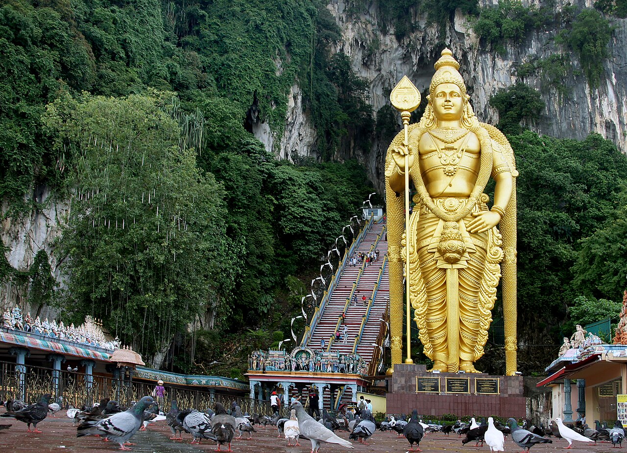 Rock climber scaling limestone cliff face at Batu Caves climbing area near Kuala Lumpur Malaysia