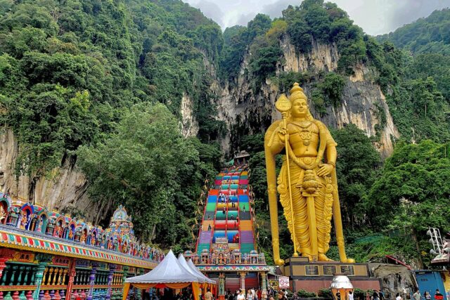 Rainbow-painted stairs and the gold Murugan statue at Batu Caves near Kuala Lumpur