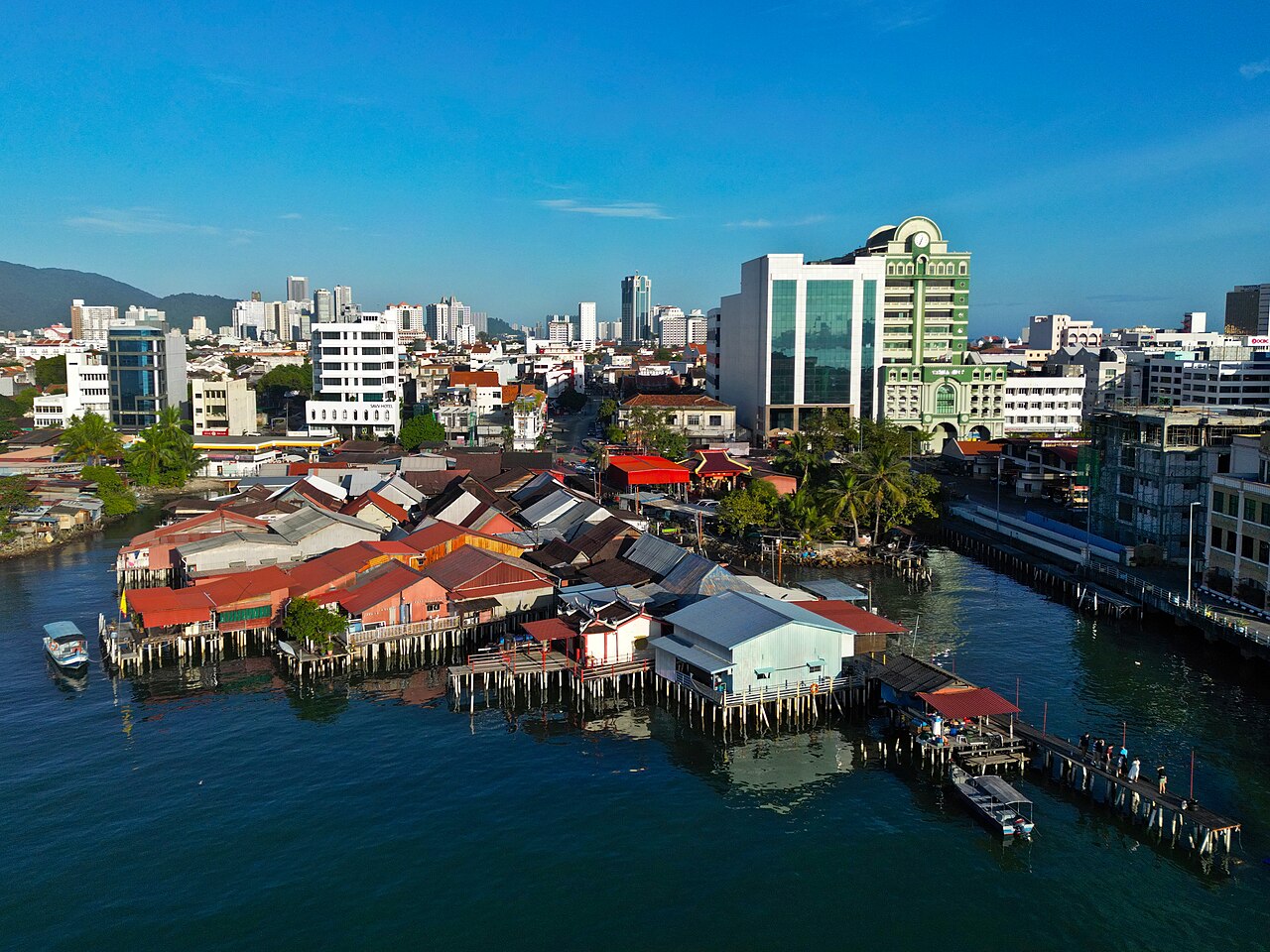 Stilt houses of a Penang clan jetty over the water with the George Town skyline behind