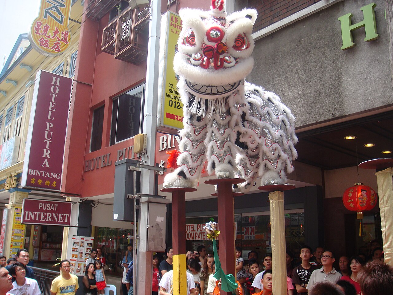 A lion dance troupe performing on poles in a Kuala Lumpur street