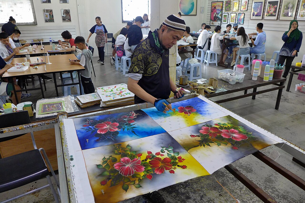 Visitors painting hibiscus-motif batik panels at a batik workshop in Kuala Lumpur