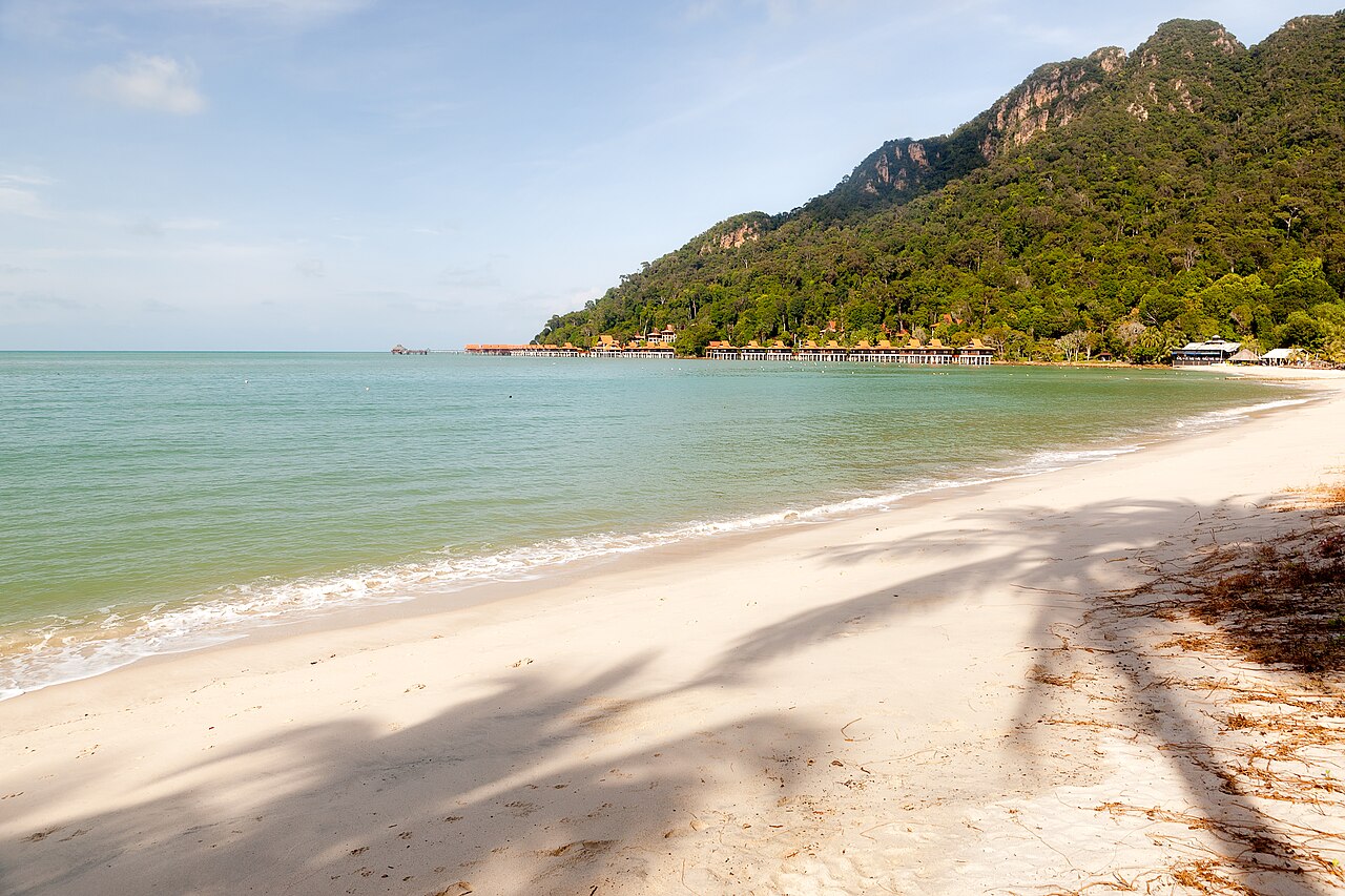 A wide sandy beach backed by forested hills on Langkawi