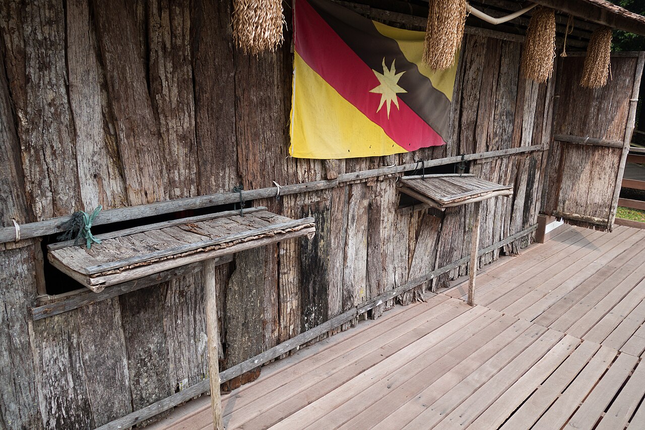 The timber verandah of a longhouse at the Sarawak Cultural Village, with the Sarawak flag hung on the wall