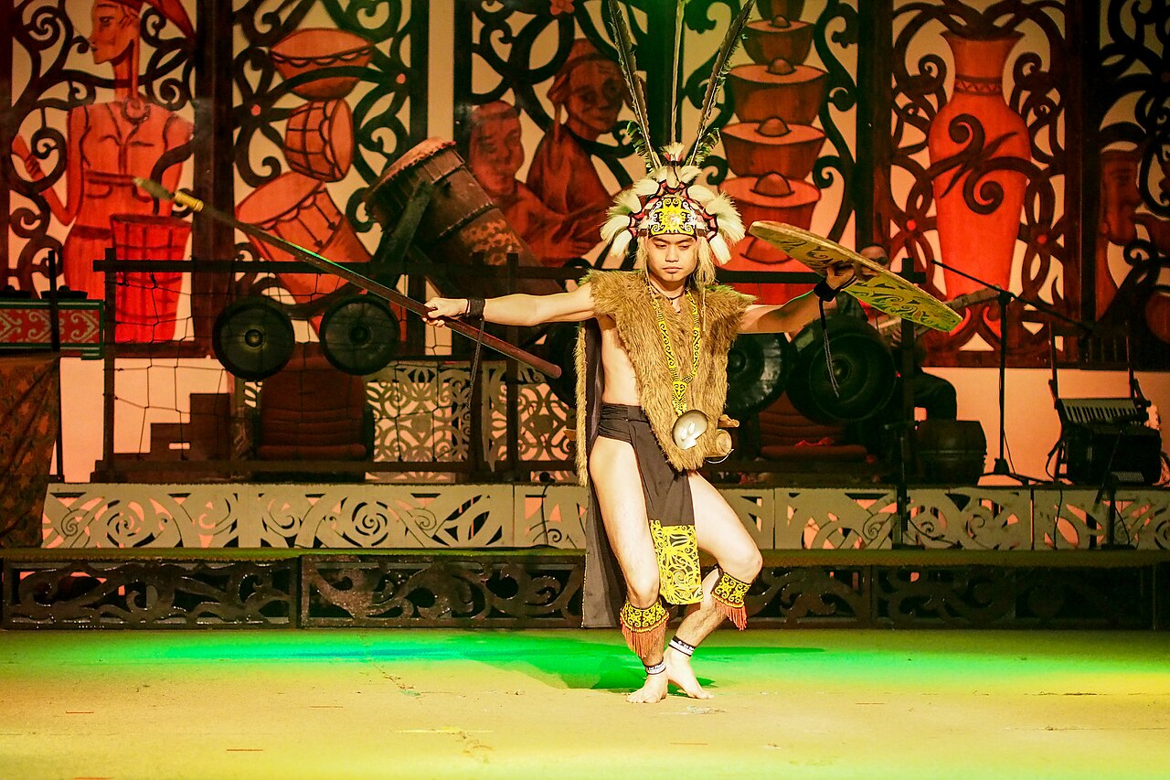 A dancer in feathered headdress and hornbill-motif costume performing the Iban ngajat